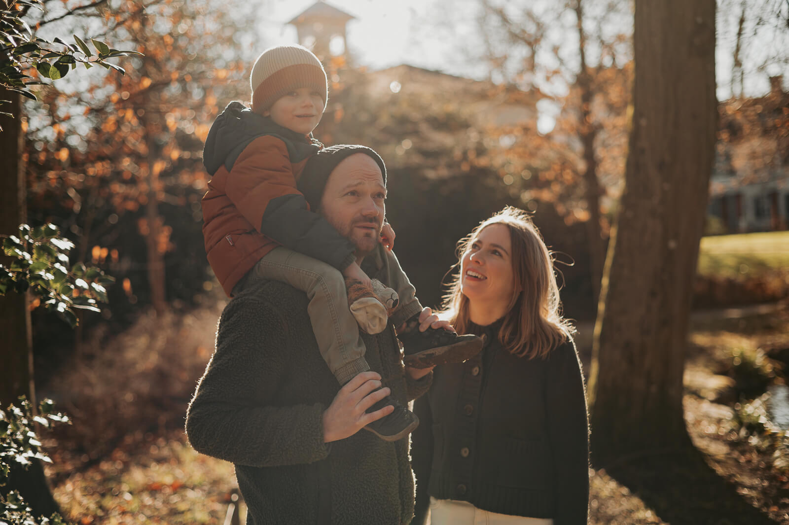 Familienfoto, Papa trägt sein Kind auf den Schultern, Mama läuft daneben.