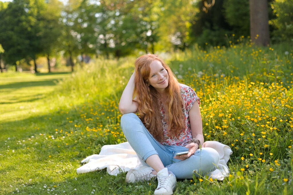 Frau sitzt auf Decke auf einer Wiese